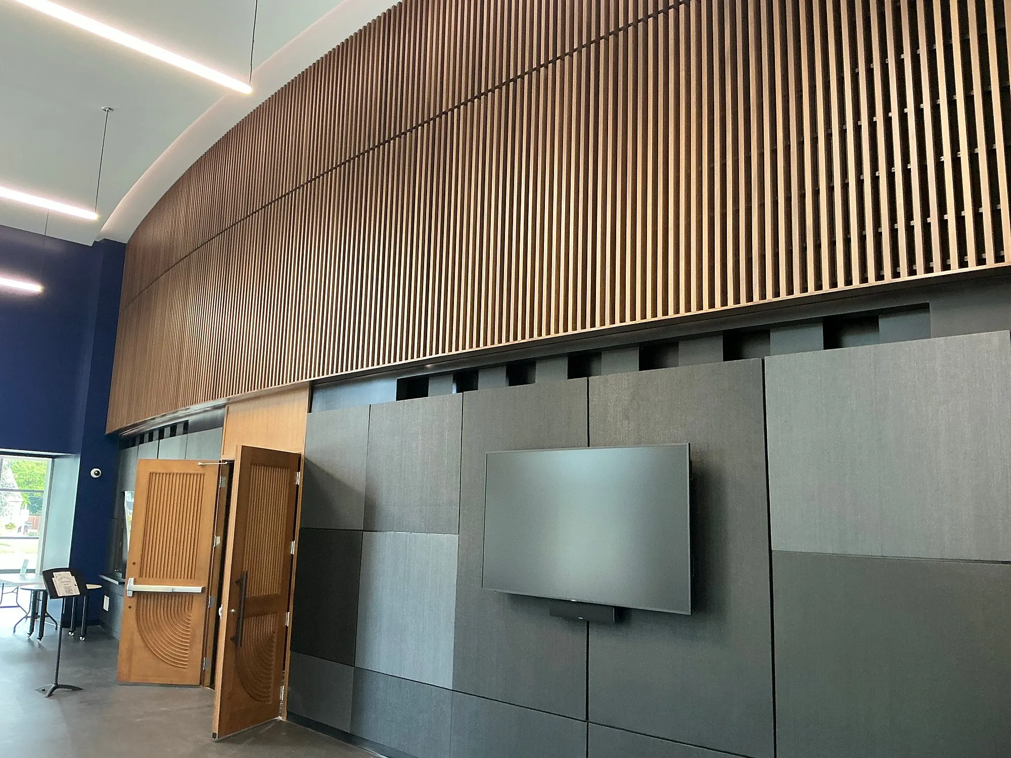 Wood-slat feature wall above new doors and dark wall panels inside Berkley High School