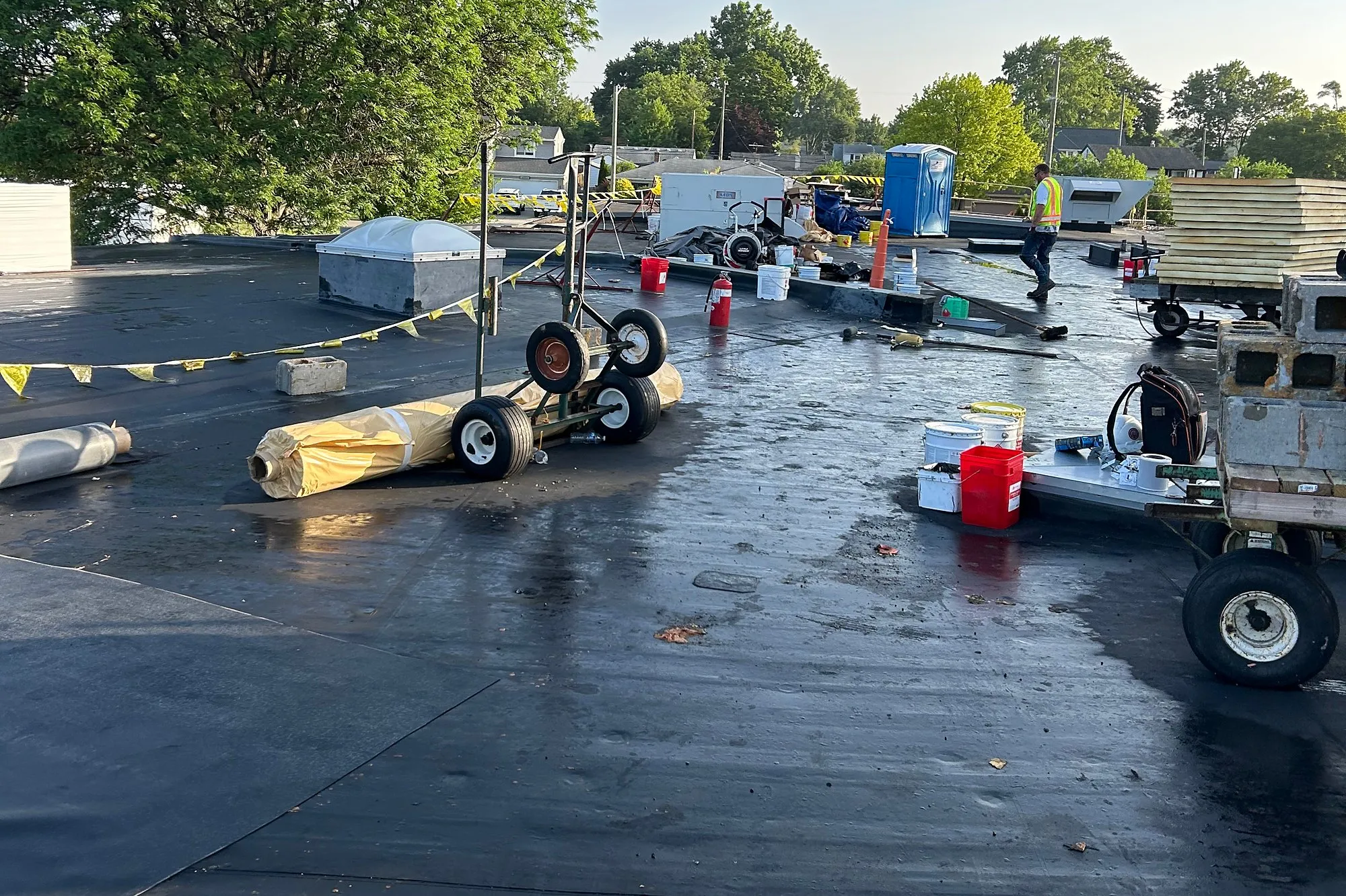 Roofing crew equipment and material rolls staged on a school roof