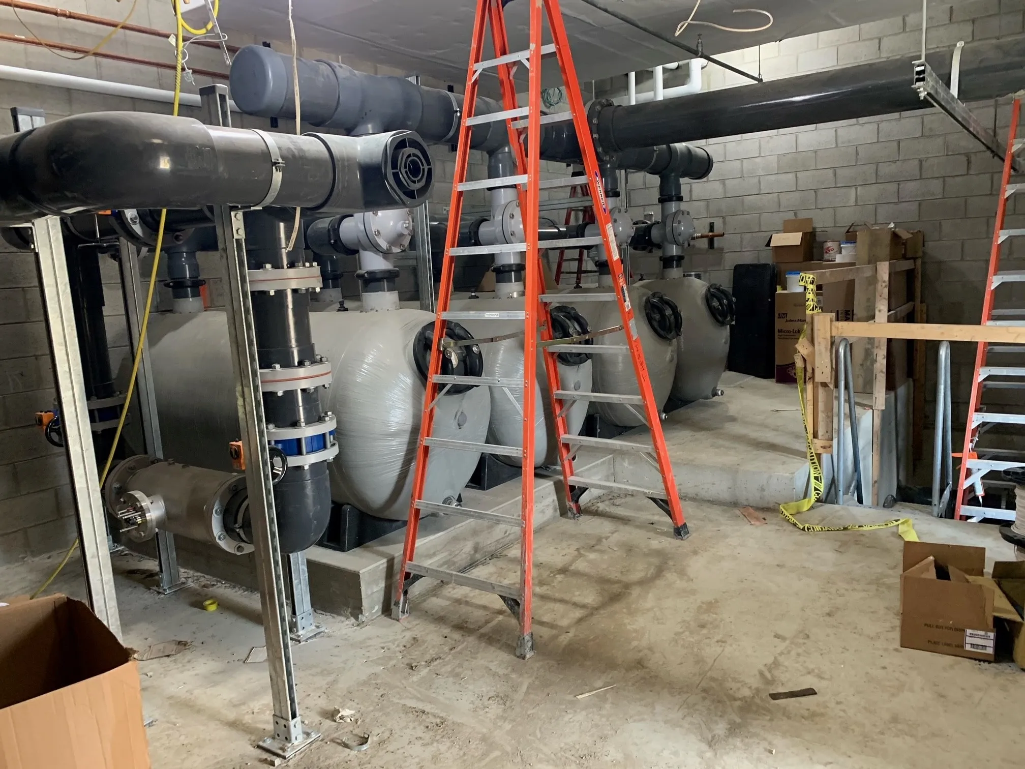 Pool mechanical room under construction with filter tanks and piping